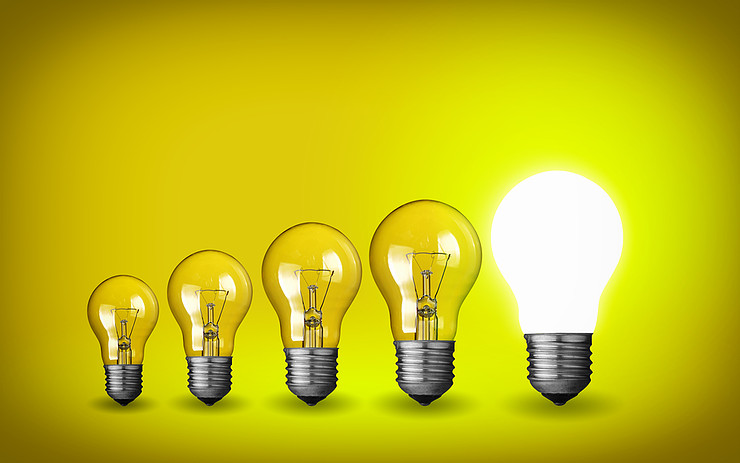 Row of lightbulbs on yellow background, rightmost lit