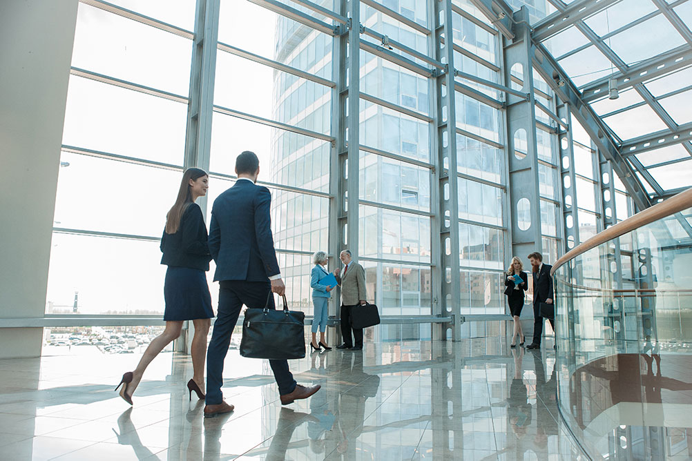 Business people strolling by plate glass windows in modern building