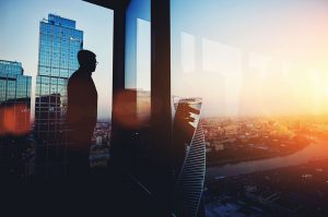 Bankruptcy image – business man overlooks city at sunset